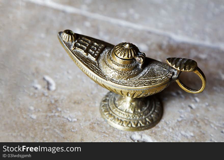 Brass oil lamp on marble tiling