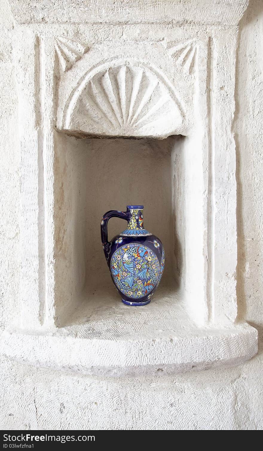 Very ornate hand painted ceramic wine water jug with fish motif in ornamental man made limetone alcove. Very ornate hand painted ceramic wine water jug with fish motif in ornamental man made limetone alcove