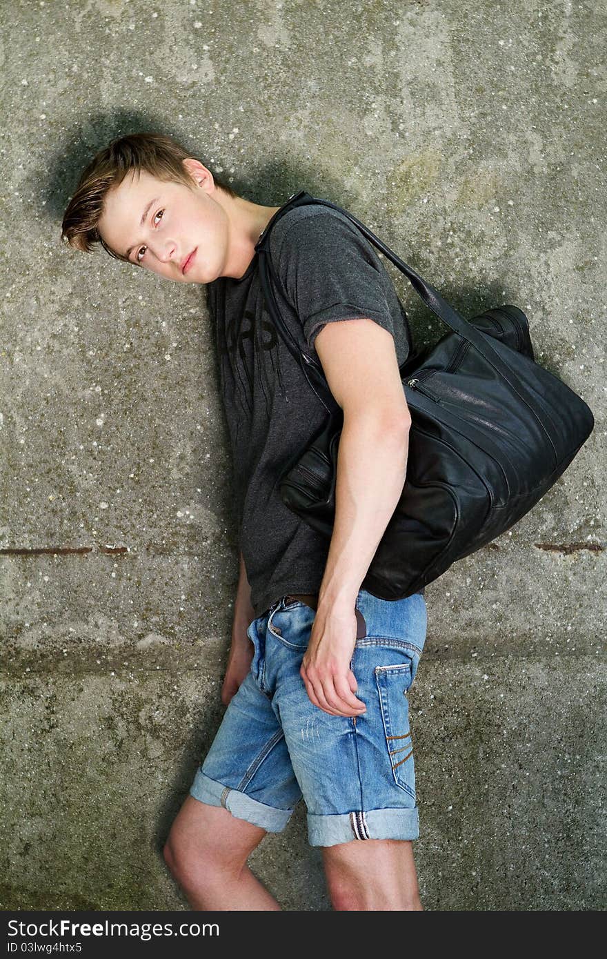 Young man near the wall with bag. Young man near the wall with bag