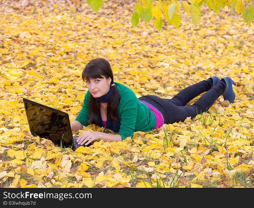 Young girl with a laptop in a autumn foliage