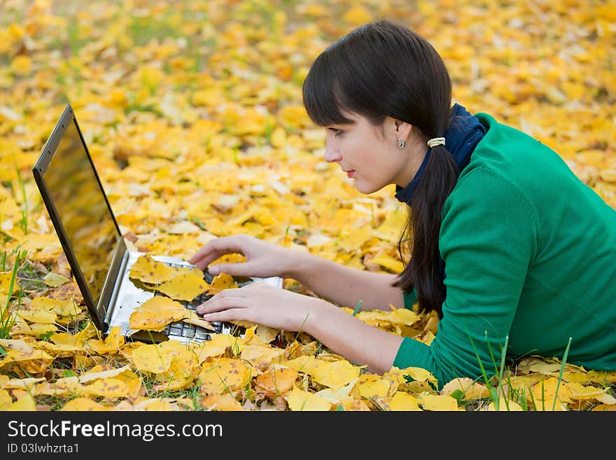 Young girl with a laptop in a autumn foliage