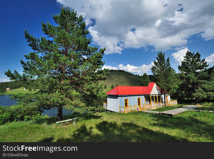 Log Cabin under blue sky and white clouds along the lake. Log Cabin under blue sky and white clouds along the lake.