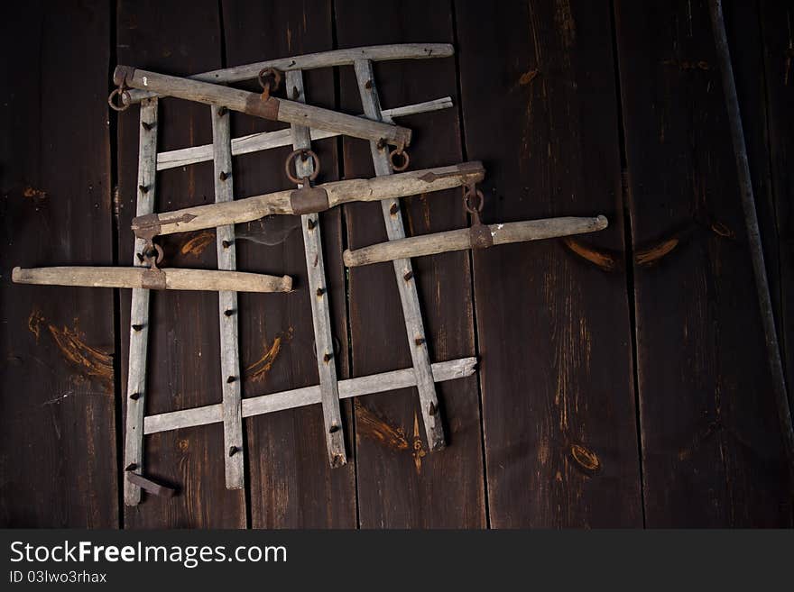 Old wooden harrow hanging on dark wooden wall. Old wooden harrow hanging on dark wooden wall.