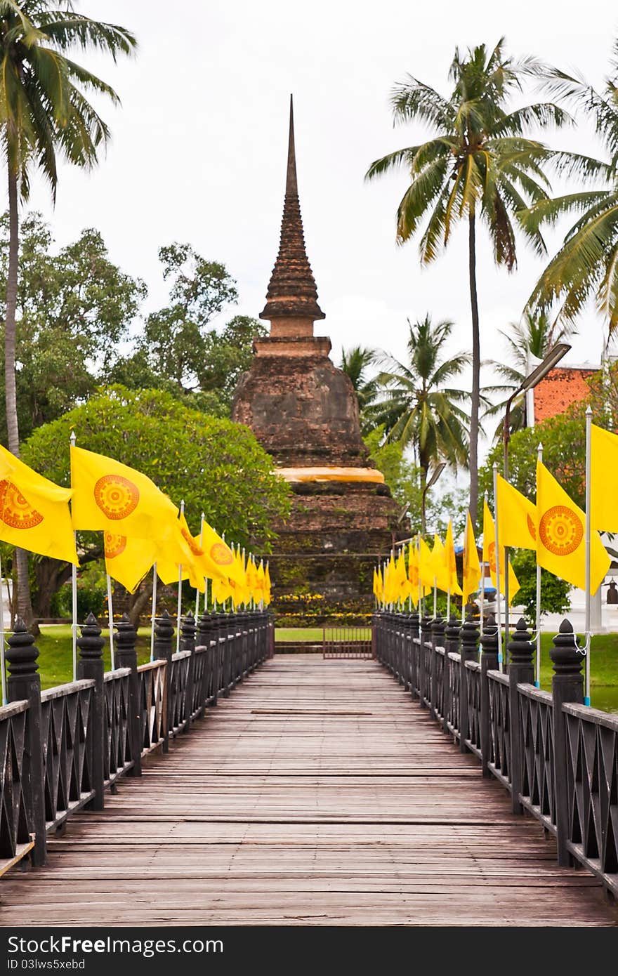 Wooden bridge to ruin pagoda with buddhist flag in Sukhothai (vertical closed up). Wooden bridge to ruin pagoda with buddhist flag in Sukhothai (vertical closed up)