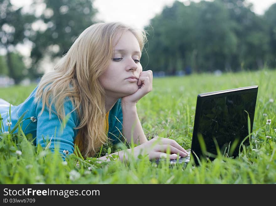 Pretty woman with laptop on the green grass