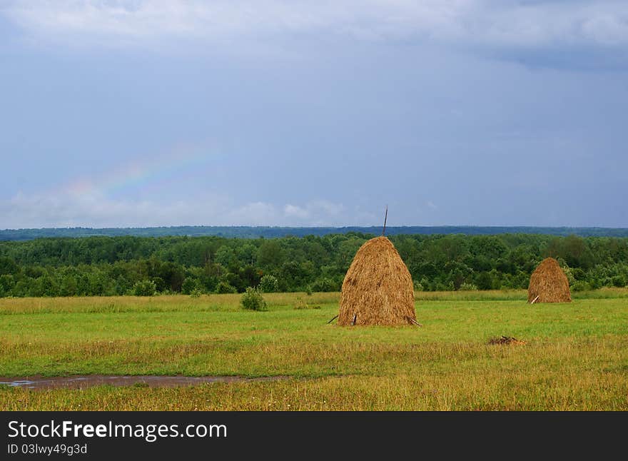 The haystack, the Russian landscape rainbow in the sky after the storm