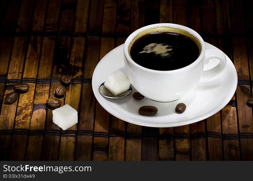 Cup of coffee ans beans on straw in night