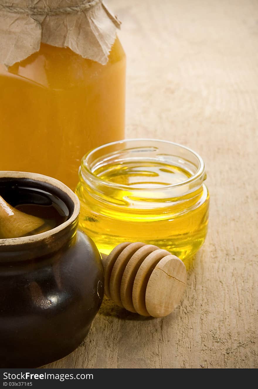 Honey in jars and pot on wood table