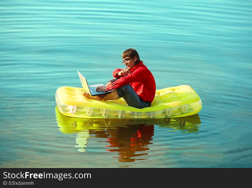 Businessman with notebook sitting on inflatable mattress. Businessman with notebook sitting on inflatable mattress