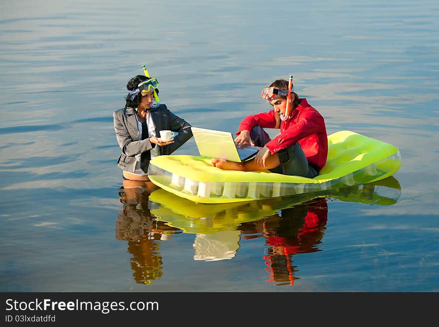 Businessman with notebook sitting on inflatable mattress and his secretary brings coffee to him. Businessman with notebook sitting on inflatable mattress and his secretary brings coffee to him.