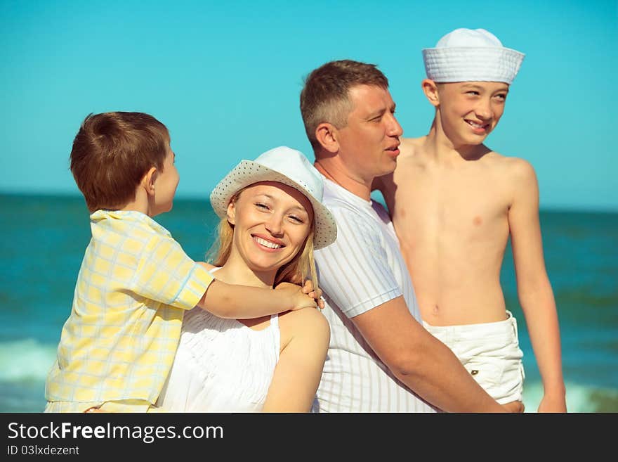 Happy family. Parents holding sons in theirs arms on beach while on vacation