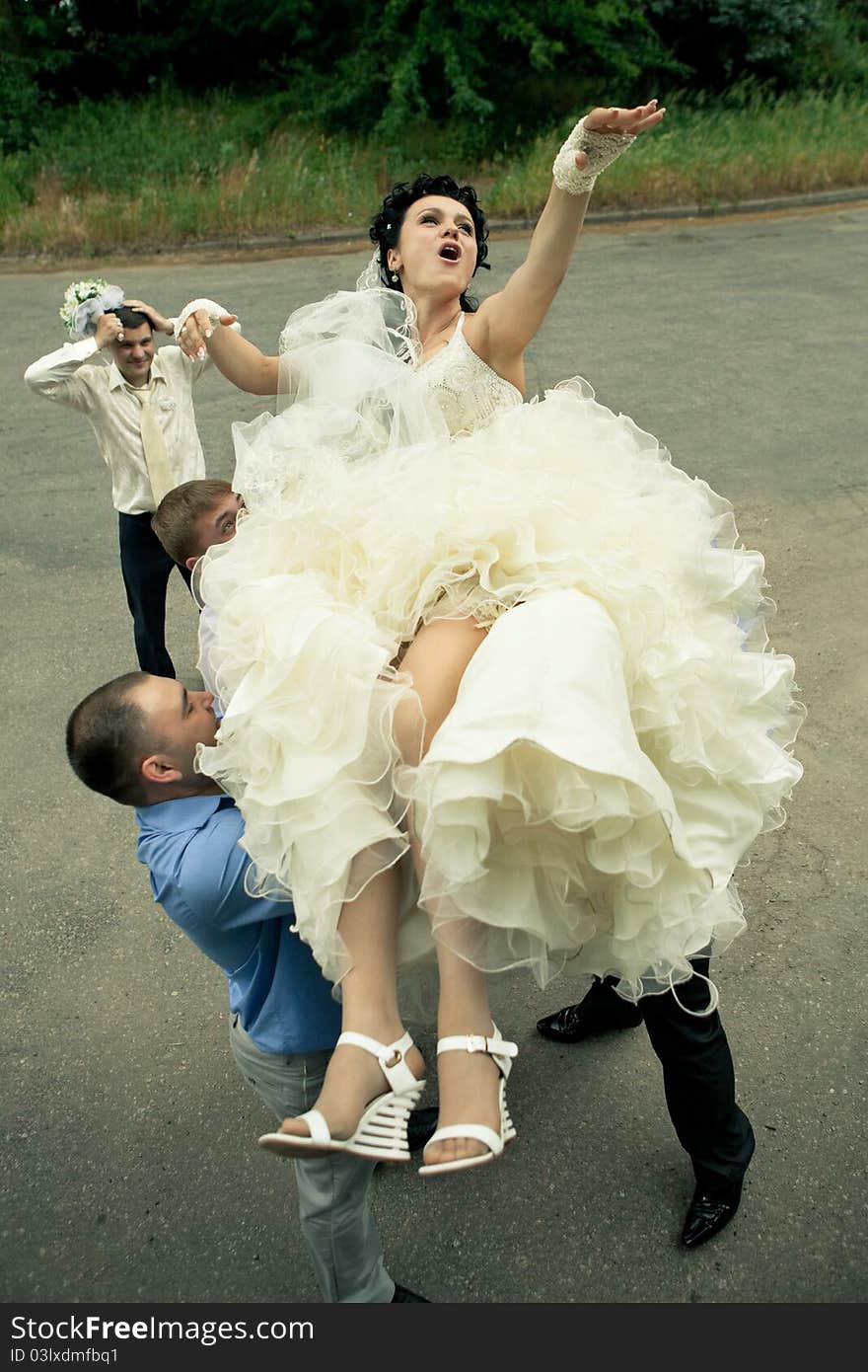 A happy bride tossed into sky by a group of groomsmen. A happy bride tossed into sky by a group of groomsmen