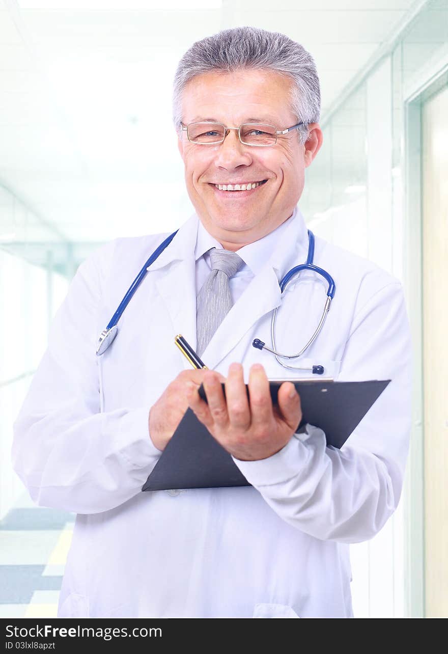 Closeup portrait of a happy young doctor with stethoscope in hospital writing a receipt. Closeup portrait of a happy young doctor with stethoscope in hospital writing a receipt