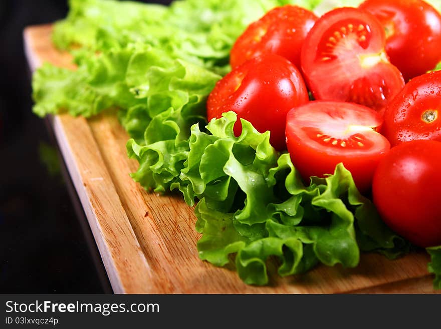 Fresh and wet tomatoes lying on the salad leaves