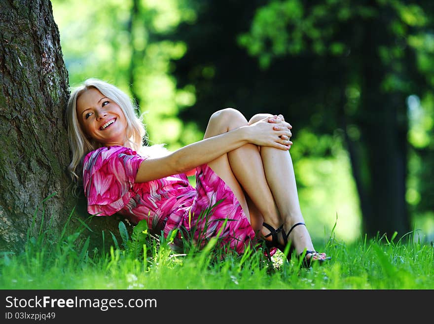 Happy girl lying under a tree on a summer day