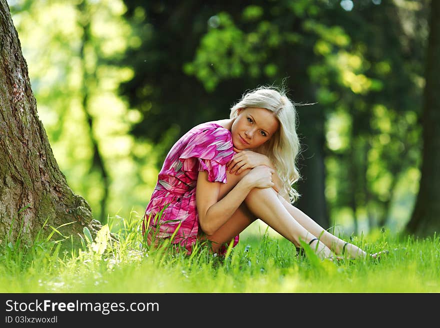 Happy girl lying under a tree on a summer day