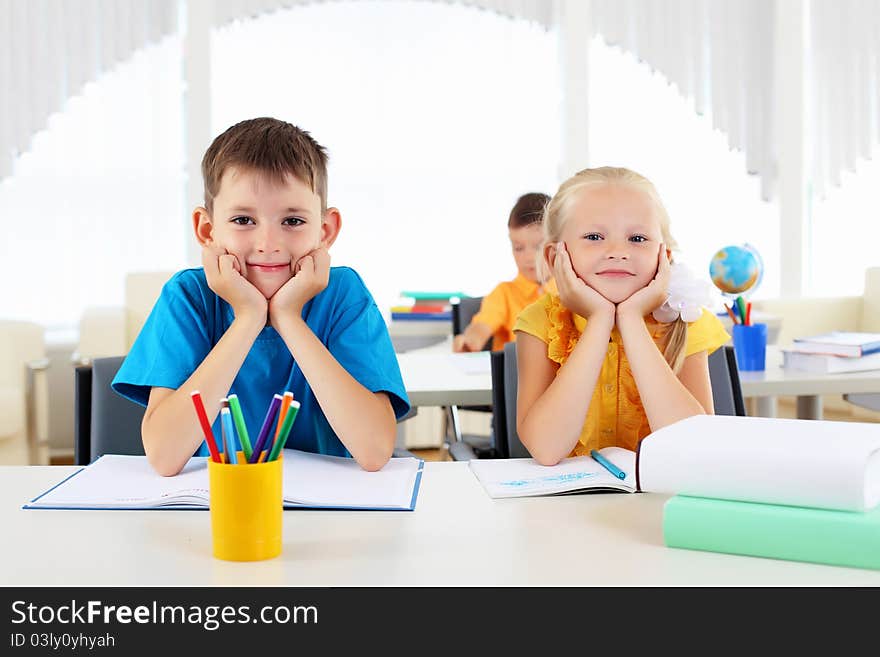 Boy and girl sitting together at a desk at school.