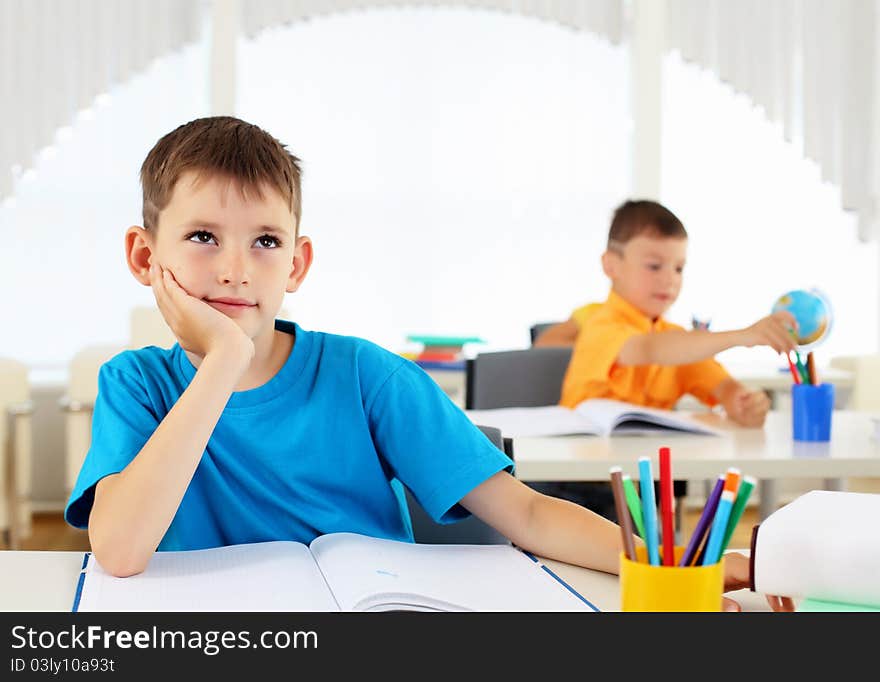 Portrait of a young boy sitting at his desk at school