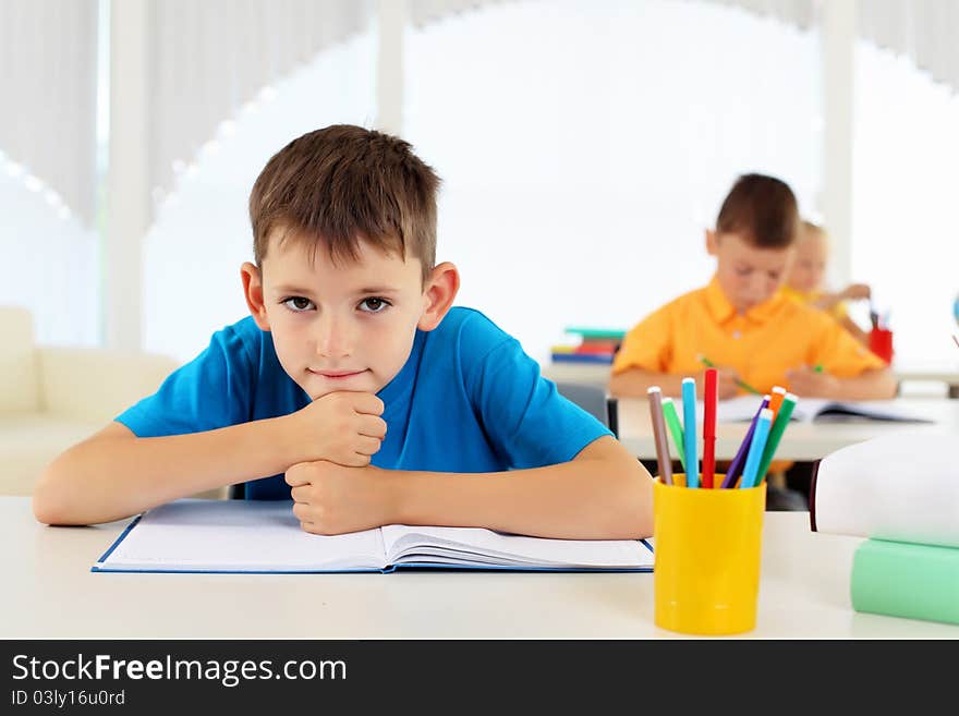 Portrait of a young boy sitting at his desk at school