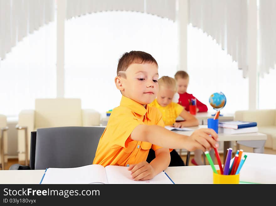 Portrait of a young boy sitting at his desk at school