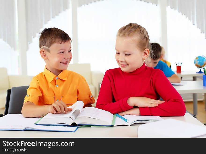 Boy and girl sitting together at a desk at school.