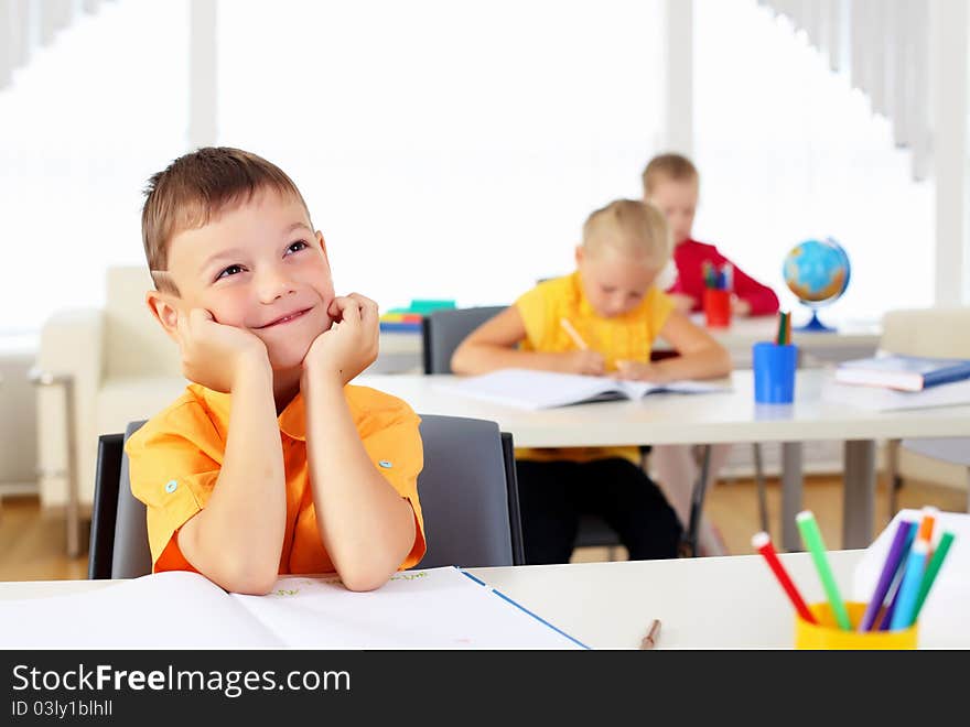 Portrait of a young boy sitting at his desk at school