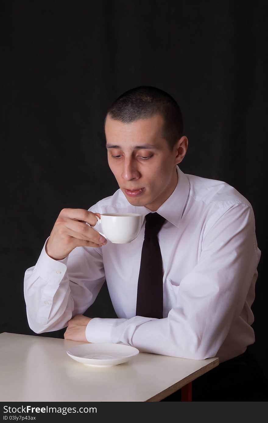 Bored businessman with cup of coffee isolated on black