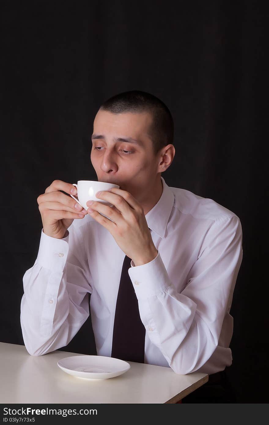 Bored businessman with cup of coffee isolated on black