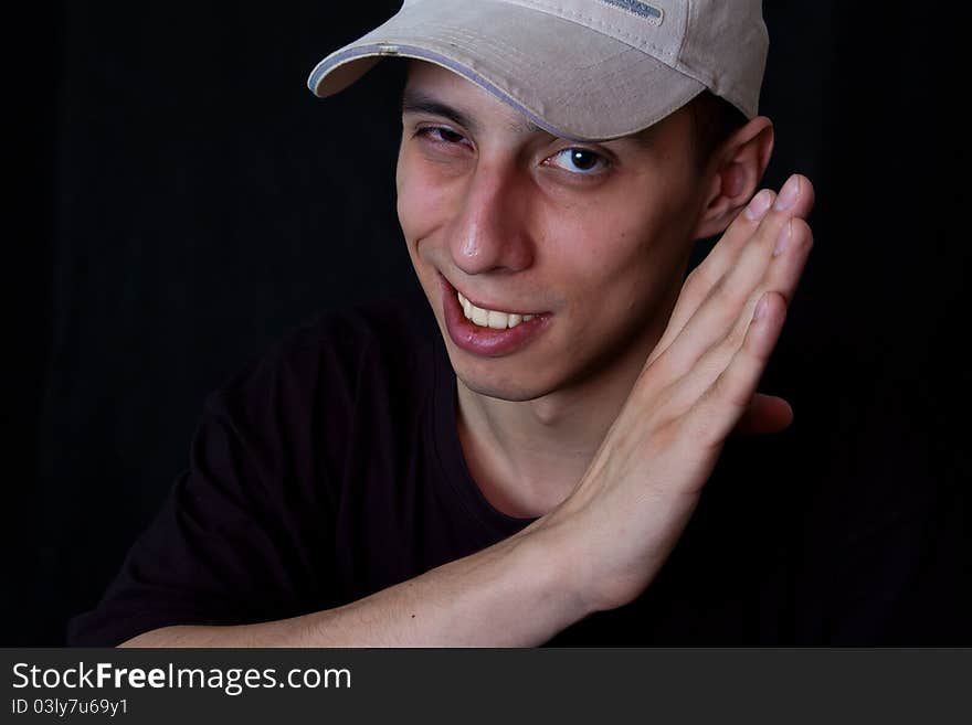 Portrait of grinning man in cap on black