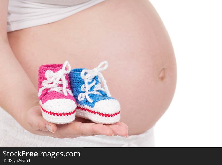 Pregnant woman holding a baby's bootees in different colours. Pregnant woman holding a baby's bootees in different colours