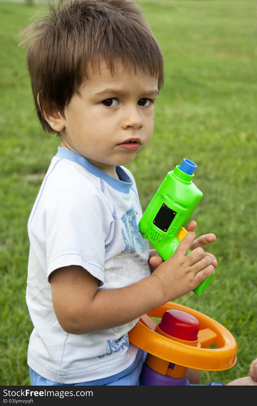 Adorable two year old boy playing with gun outside. Adorable two year old boy playing with gun outside