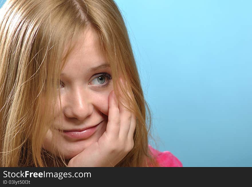 Young woman with cheesy smile; close-up shot in studio against blue background. Young woman with cheesy smile; close-up shot in studio against blue background