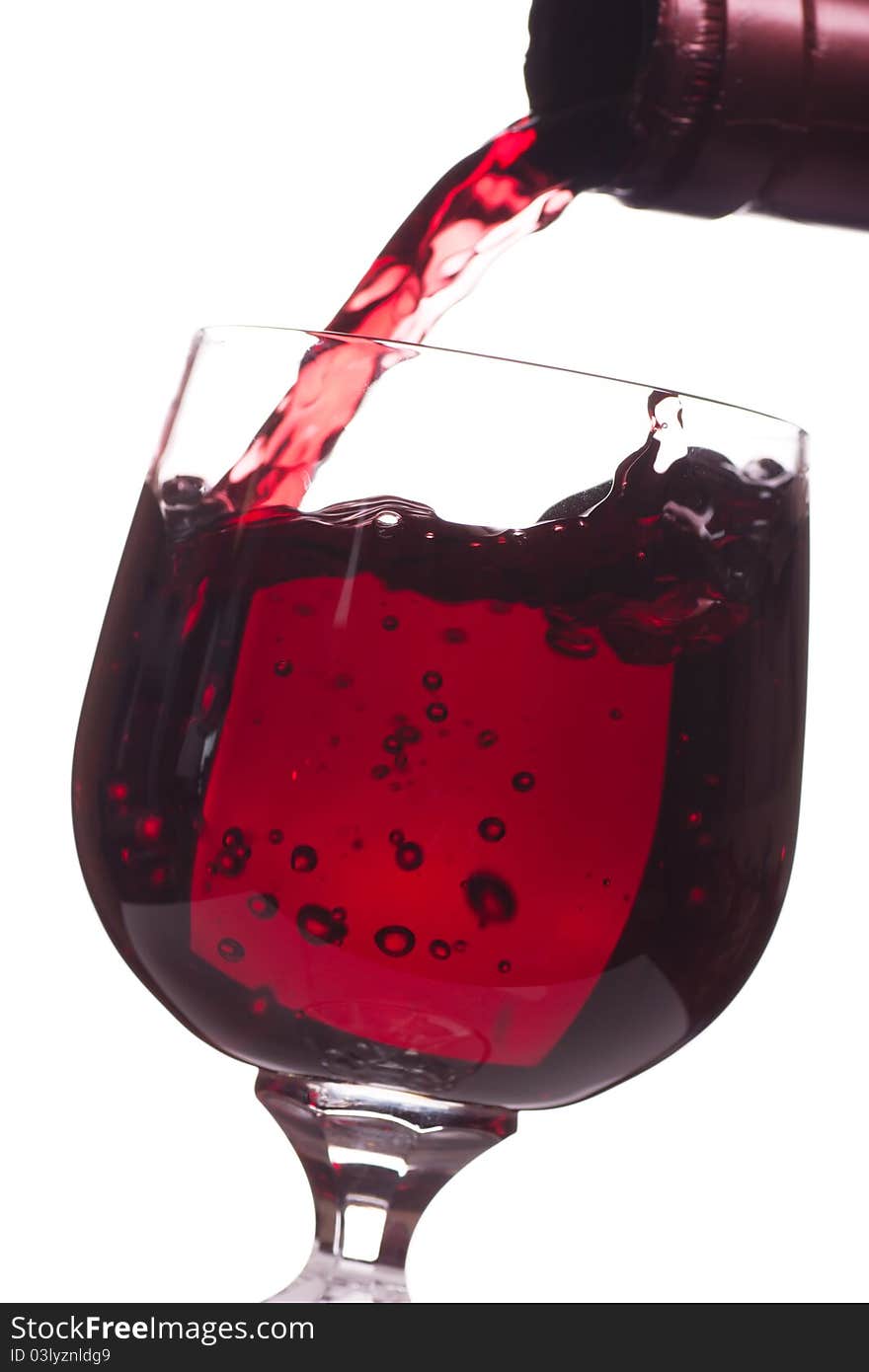 Red wine pouring down from a bottle into a glass over white background. Red wine pouring down from a bottle into a glass over white background