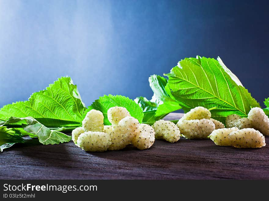 Mulberry of season on old wood and background of leaves. Mulberry of season on old wood and background of leaves