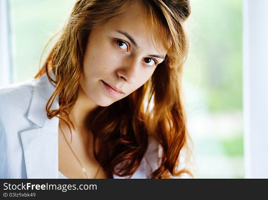 Portrait of a young casual woman sitting on window