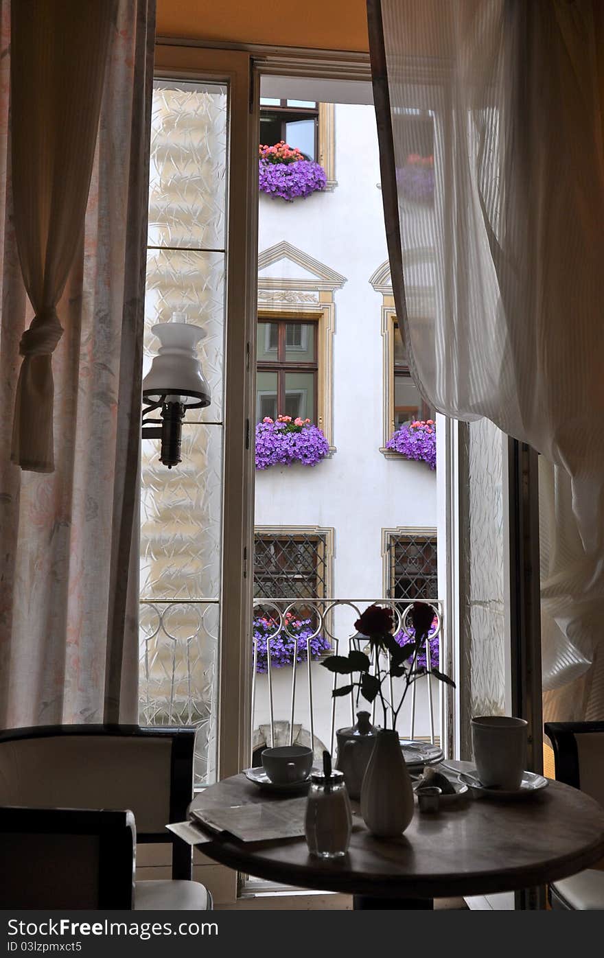 Coffee shop table with view of historic building with beautiful flowers in each window. Coffee shop table with view of historic building with beautiful flowers in each window