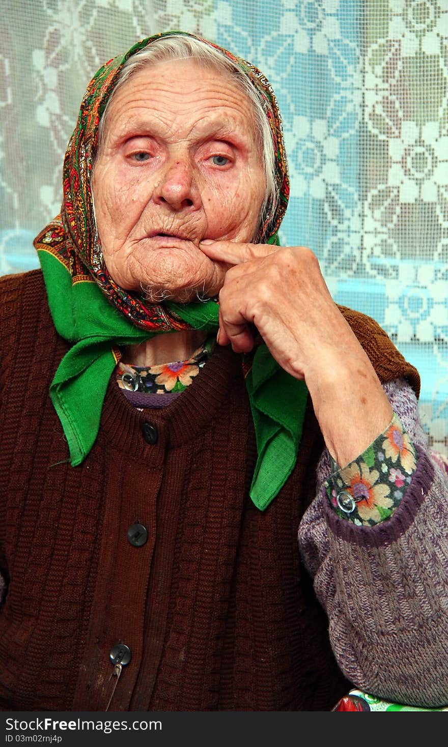 Merry grandmother sitting at the table on a background window