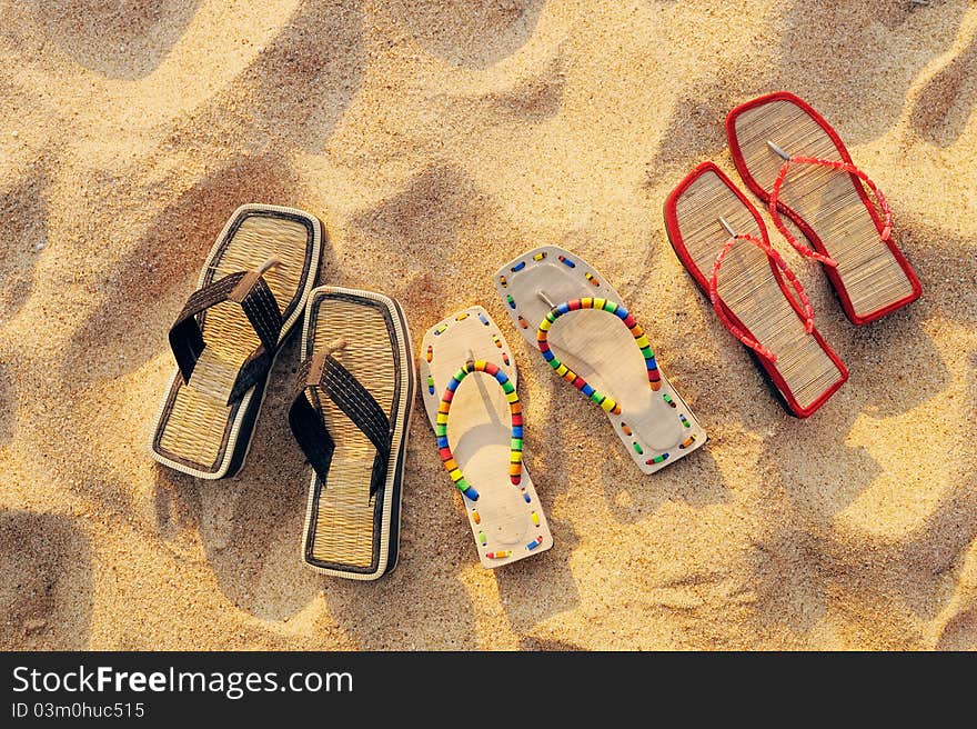 Three pair of beach sandals on the sandy beach. Three pair of beach sandals on the sandy beach