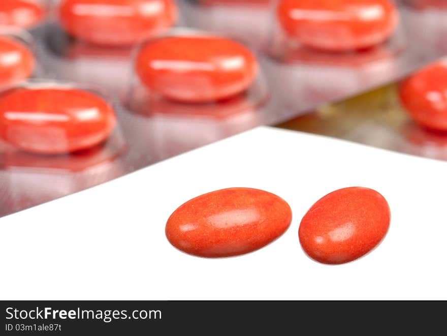 Close up orange capsules and blisters isolated on white