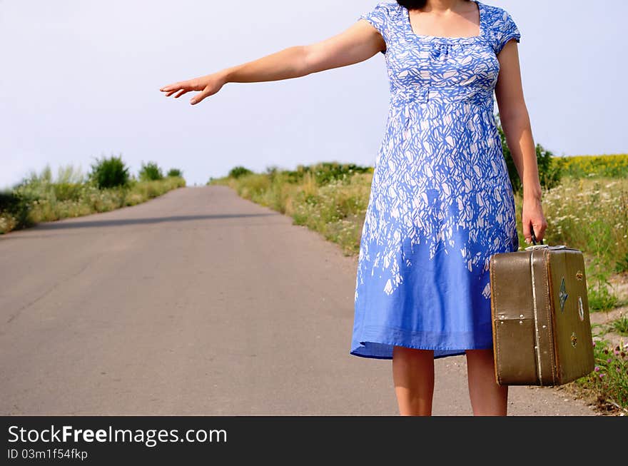 Young girl on the road with a suitcase