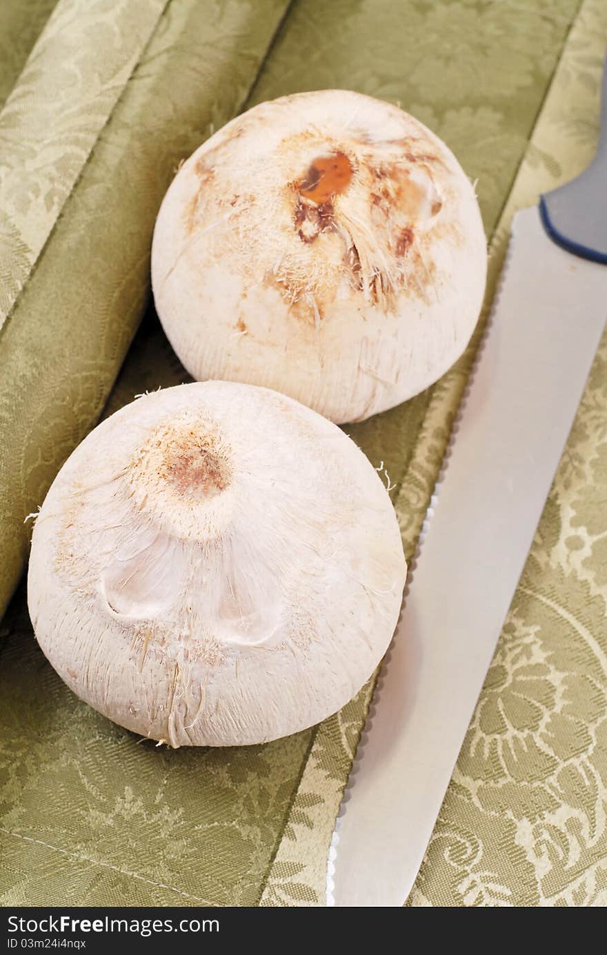 Husked Coconuts With Knife On Table Cloth