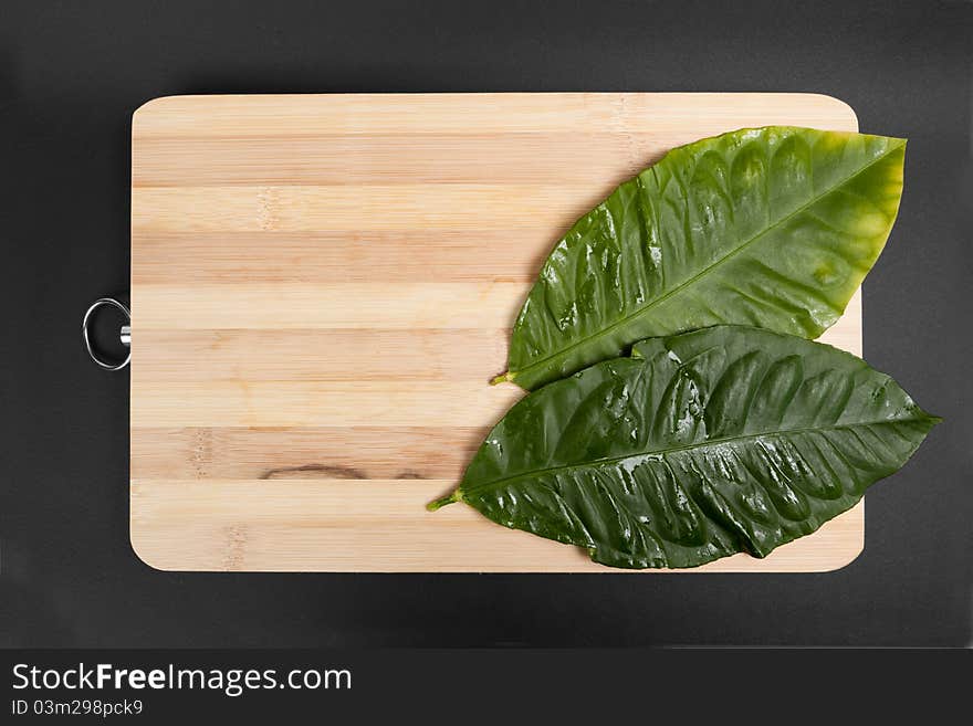 Lemon leaves into wood plates on a black background