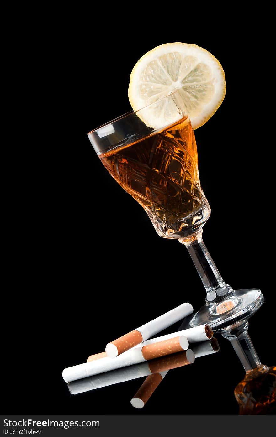 Cognac in a glass with lemon and cigarettes