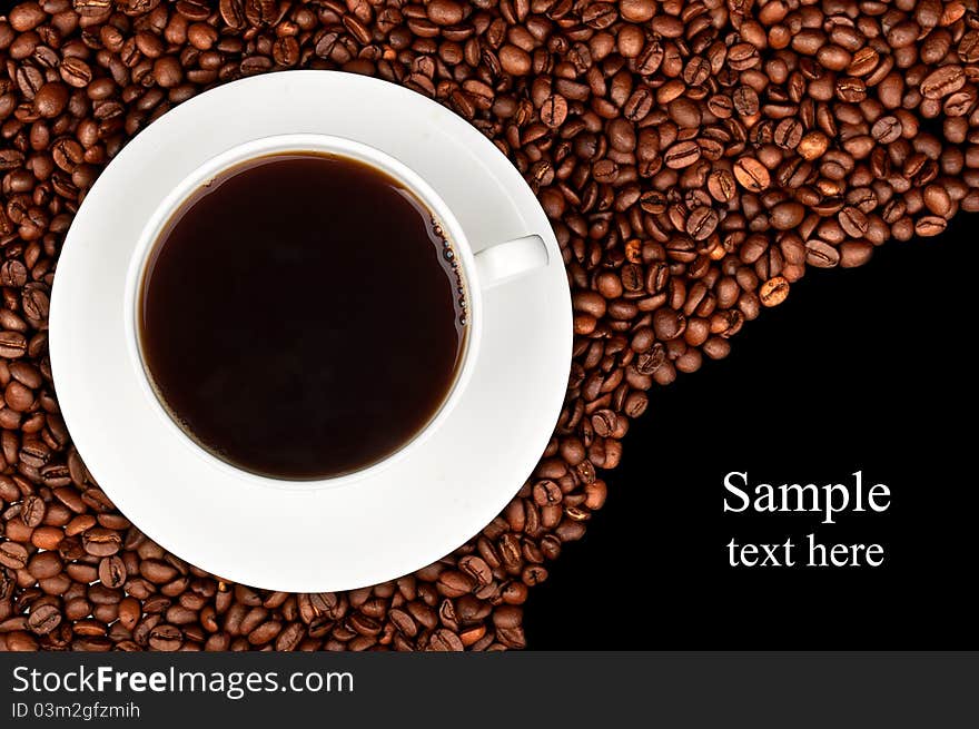 White cup with coffee and coffee beans on a black background