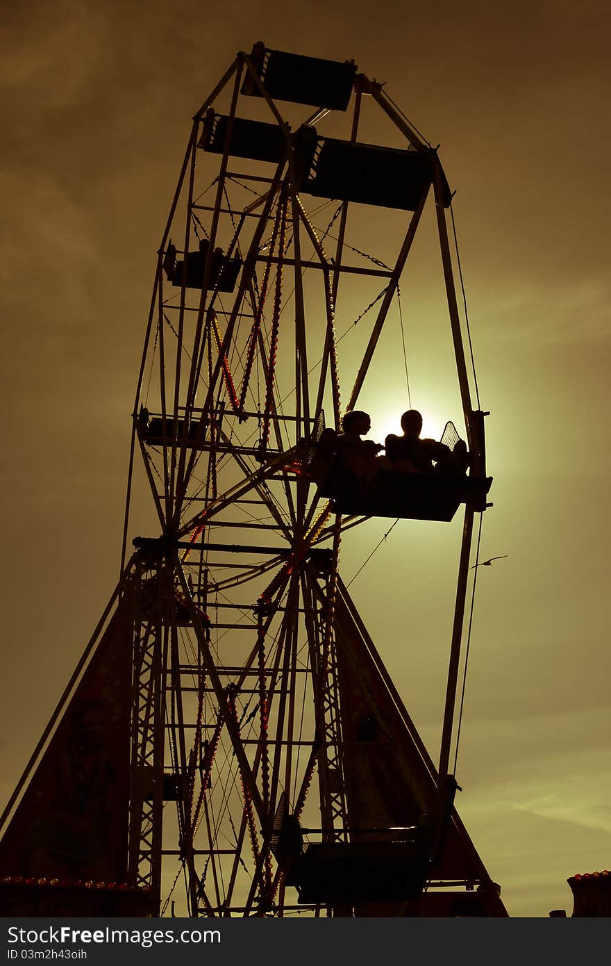 Couple riding in funfair wheel at sunset