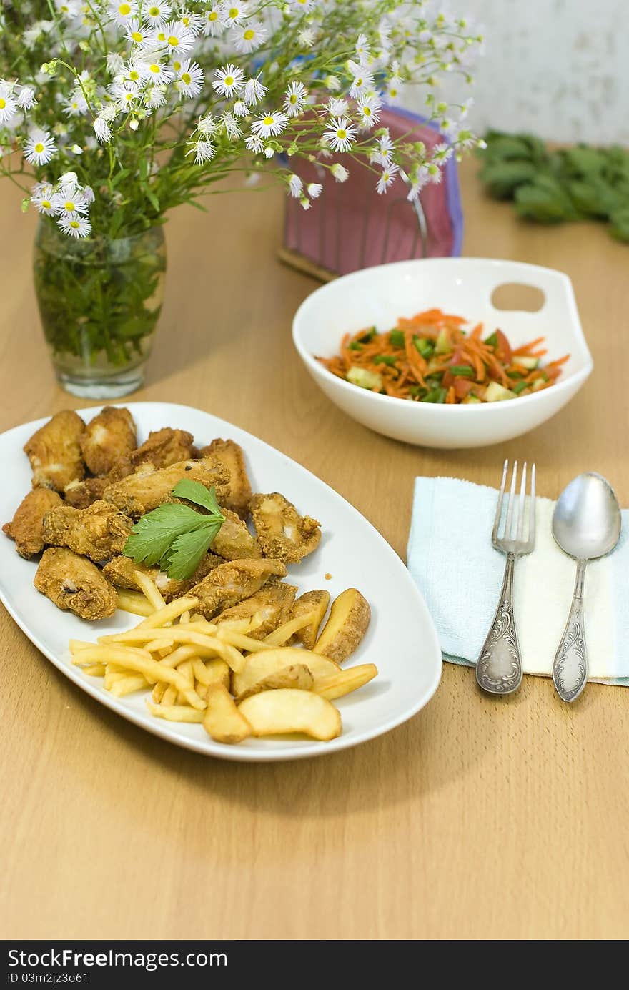 Golden fried chicken and fried potatoes in a white plate on the table