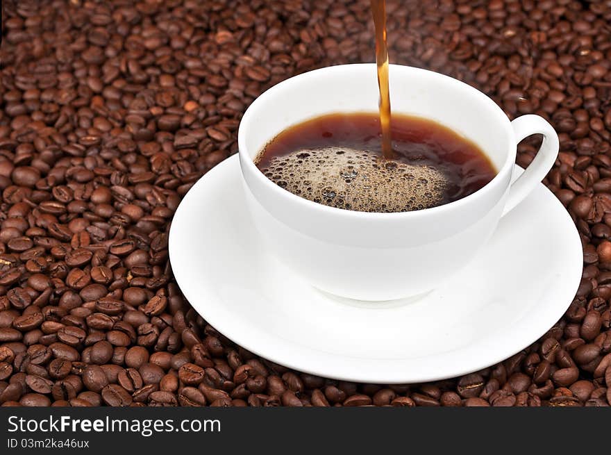 White cup with coffee and coffee beans on a background