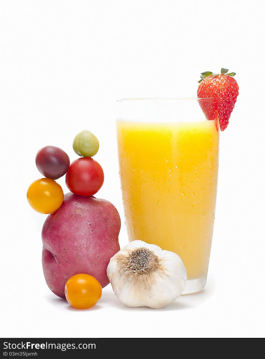 A glass of orange juice, decorated with a strawberry. Arrangement of potato, tomatoes and a garlic at the side. A glass of orange juice, decorated with a strawberry. Arrangement of potato, tomatoes and a garlic at the side.