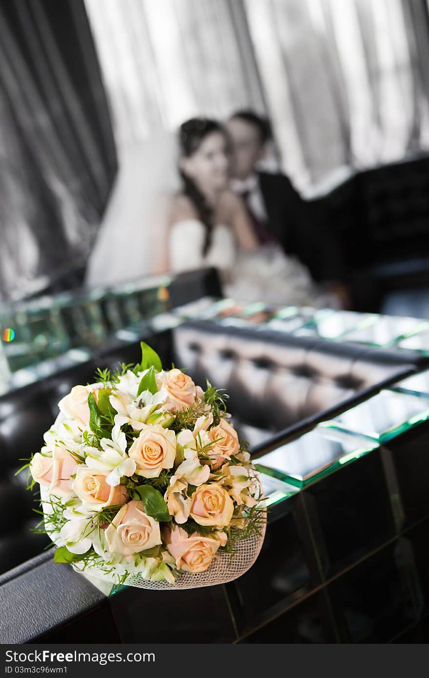 Wedding bouquet with the wedding couple in the background