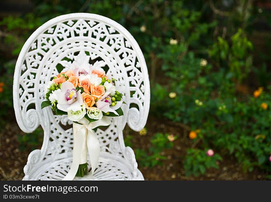 Wedding flower bouquet on a white garden chair, during a wedding